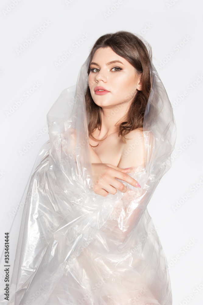 Young beautiful woman in plastic in the studio. Ecology and plastic trash concept. Young beautiful woman in plastic in the studio. Ecology and plastic trash concept.