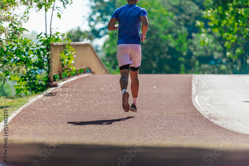 Athletic young man running on the race track in a sports park © qunica.com