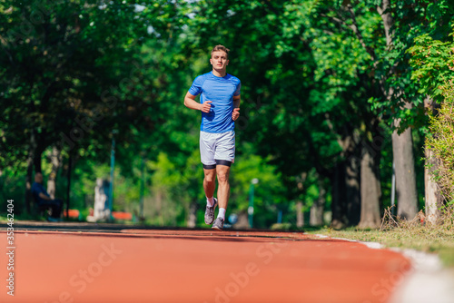 Strong athletic man jogging on the running track