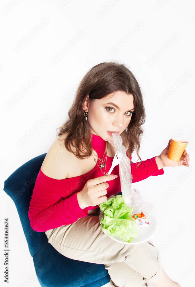 Young beautiful woman eating a plastic bag as a concept of plastic contaminated food. Ecology concept. Young beautiful woman eating a plastic bag as a concept of plastic contaminated food. Ecology concept.