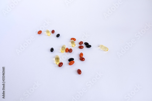 Mix of colorful vitamins and omega-3 fish oil in the form of capsules on a white background.