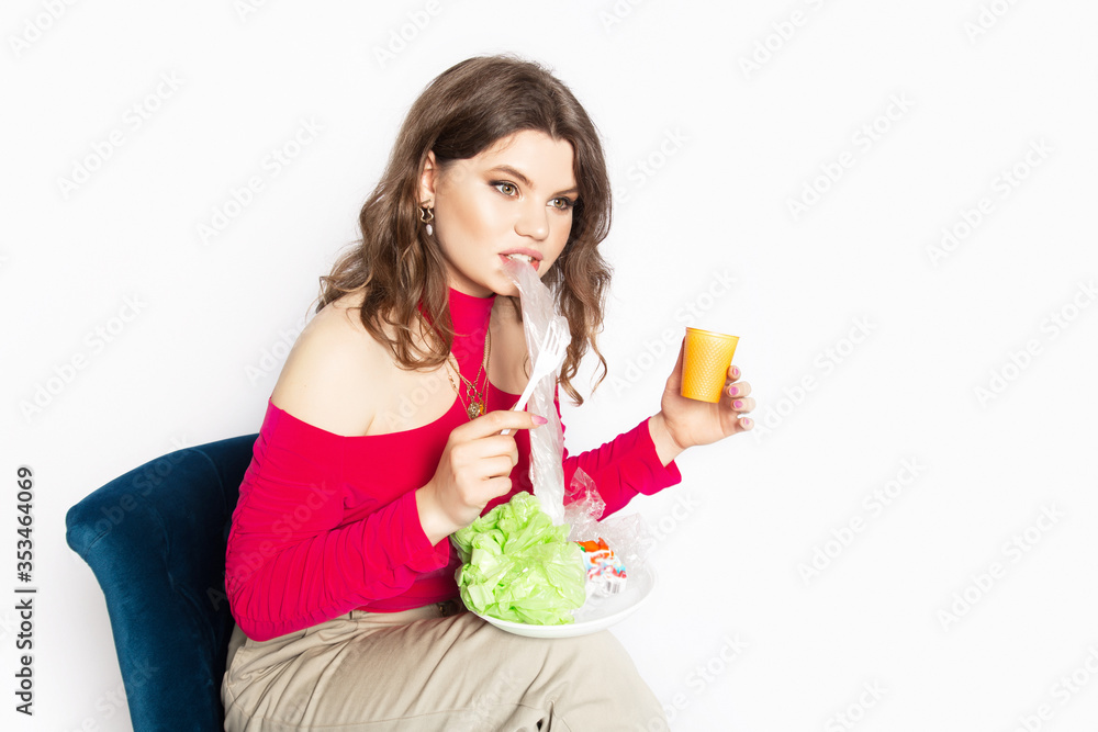 Young beautiful woman eating a plastic bag as a concept of plastic contaminated food. Ecology concept. Young beautiful woman eating a plastic bag as a concept of plastic contaminated food. Ecology concept.