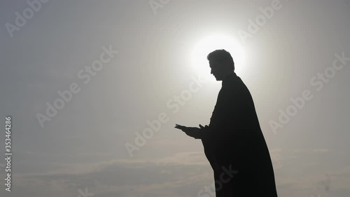 The priest in the mantle reads the Orthodox Bible at the sea, side view.