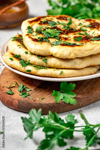 Freshly baked homemade flatbread with oil, spices and parsley. Traditional homemade wheat flour bread on a plate close-up.