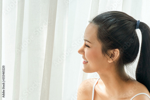 Beautiful asian woman just woke up and laying on the bed  smile and looking outside. Sexy look in the morning time. Copy Space.