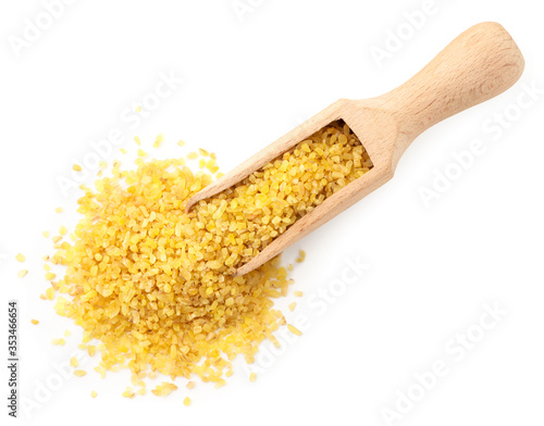Dry bulgur in a wooden spatula on a white background isolated. The view from top