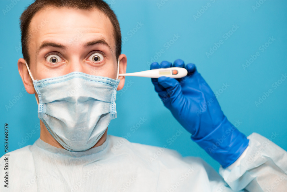 Handsome doctor man in protective mask and gloves hold medical thermometer set 40 isolated on blue background. Handsome doctor man in protective mask and gloves hold medical thermometer set 40 isolated on blue background.