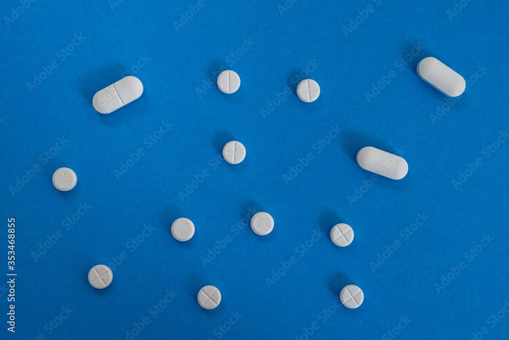 top view of white round and oval tablets on blue background