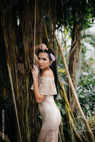 A young beautiful brunette posing among dense thickets of jungle and rainforest. Spa