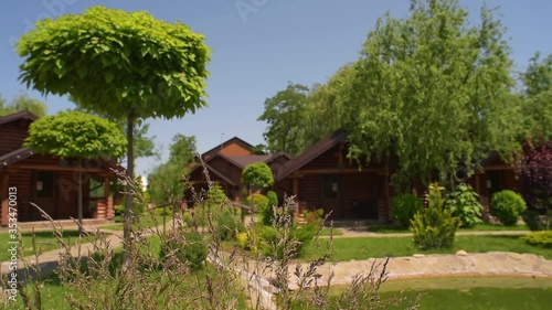 Wallpaper Mural Log cottages on the background of trees and flowering shrubs outside the city, houses made of eco - friendly materials of traditional construction Torontodigital.ca