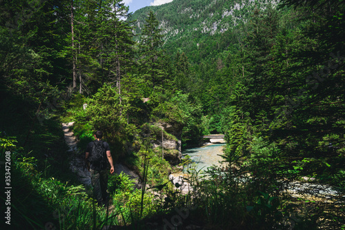 Young man hiking alone through the forest of Triglav National Park along a Soca River. Slovenia 2019