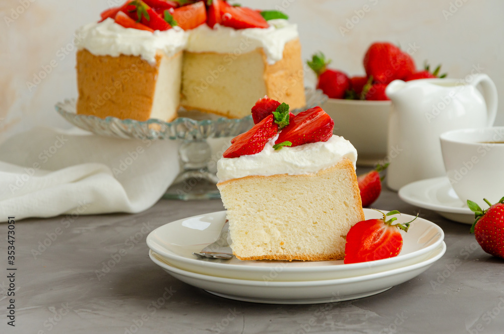 Angel food cake with whipped cream and slices of fresh strawberries on top on a concrete background. Summer dessert. Horizontal orientation, copy space. Angel food cake with whipped cream and slices of fresh strawberries on top on a concrete background. Summer dessert. Horizontal orientation, copy space.