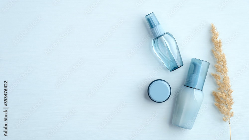 Blue toiletry cosmetic bottles and dry flower on blue background. Top view, flat lay. Water based beauty products set, minimalist style. Blue toiletry cosmetic bottles and dry flower on blue background. Top view, flat lay. Water based beauty products set, minimalist style.