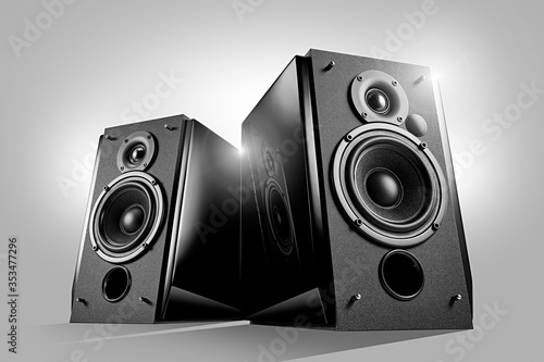 Black glossy music speakers on light grey background. Hero view shot. Audio technics. Reflection in the piano lacquer surface