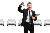 Car dealer holding a car key and documents in front of silver cars