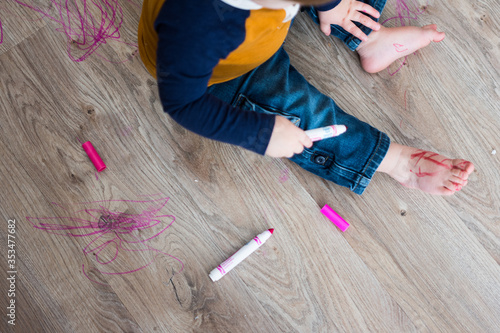 Little boy draws with marker on floor