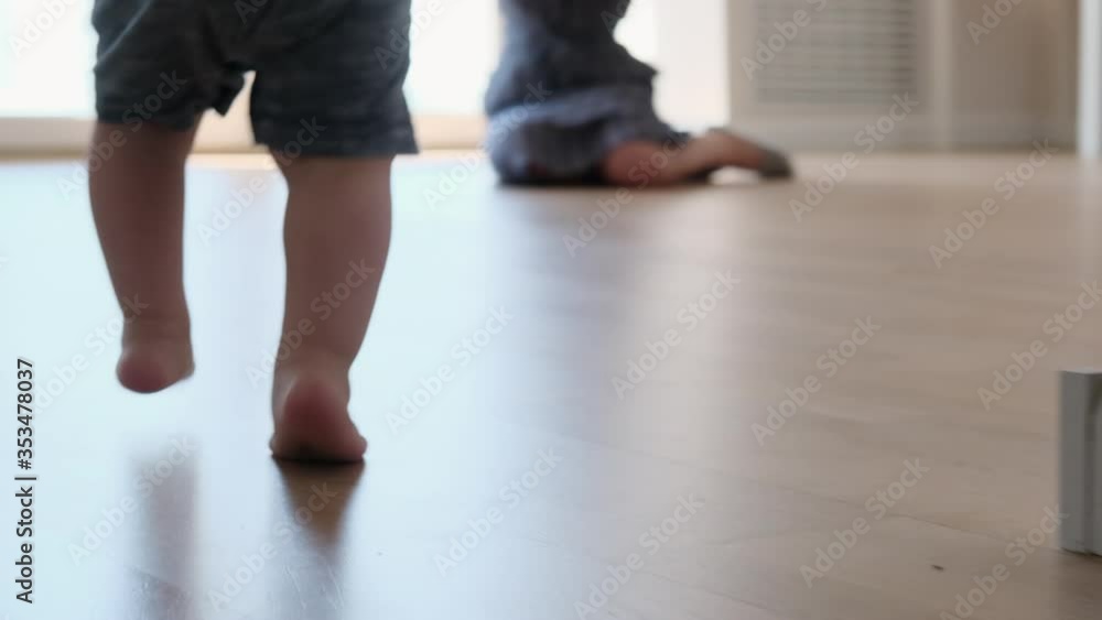 Little feet walking on floor, close-up. Baby learning to walk at home. Baby first steps. Slow motion Little feet walking on floor, close-up. Baby learning to walk at home. Baby first steps. Slow motion