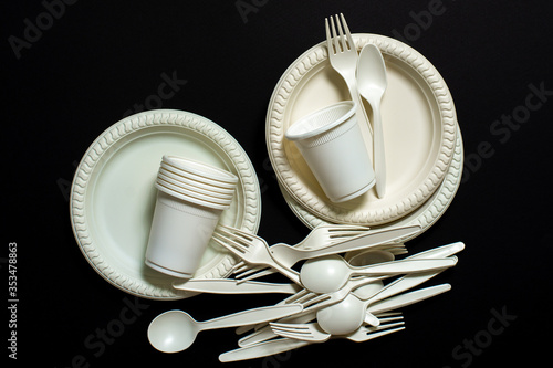 Sets of biodegradable disposable tableware on a black background. Spoons, forks, plates, glasses of corn starch. isolate. environmentally friendly modern ecological biomaterials, plastic replacement. 