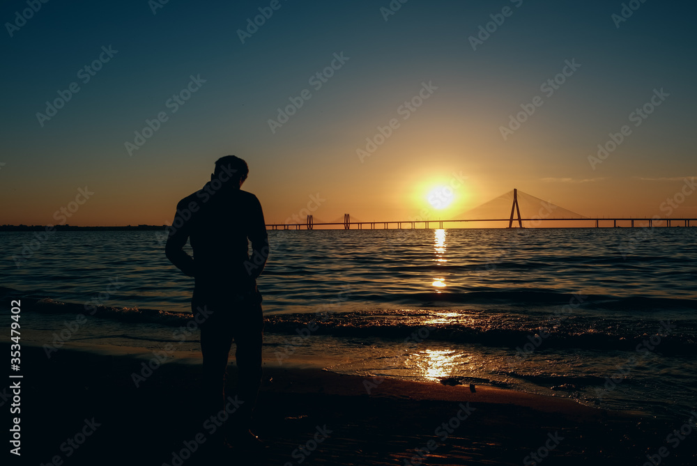 silhouette of a man walking on the beach,  Background the Bandra-Worli Sealink bridge, Mumbai City, Beautiful Sunset