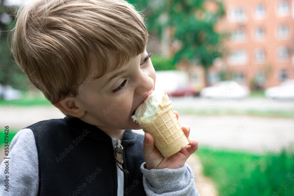 little child bites a slice of ice cream in the park on a background of nature. Delicious dessert on a summer day. close-up portrait little child bites a slice of ice cream in the park on a background of nature. Delicious dessert on a summer day. close-up portrait