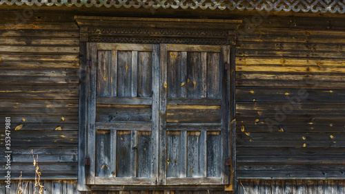 Rustic house wall with closed window and cracked paint. Space for text. Countryside concept.