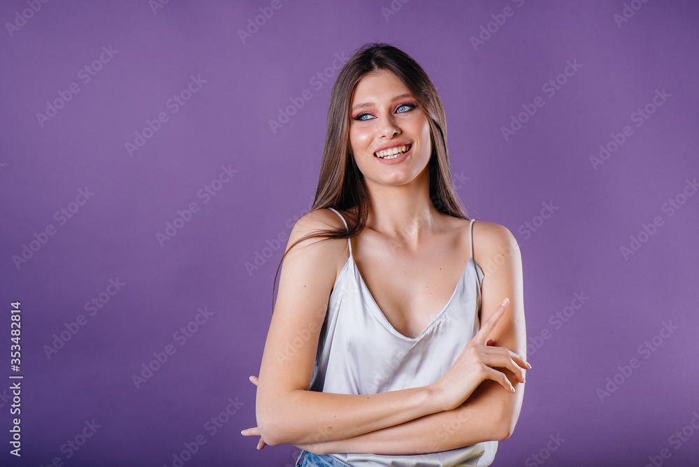 A young beautiful girl shows emotions and smiles in the Studio on a purple background. Girls for advertising A young beautiful girl shows emotions and smiles in the Studio on a purple background. Girls for advertising