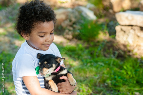 African young boy holding his little dog in nature.