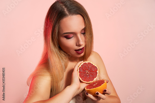 Beautiful girl with grapefruit, isolated in studio background. Beauty fashion shooting, space for text, food nutrition concept