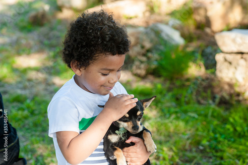 African young boy holding his little dog in nature.