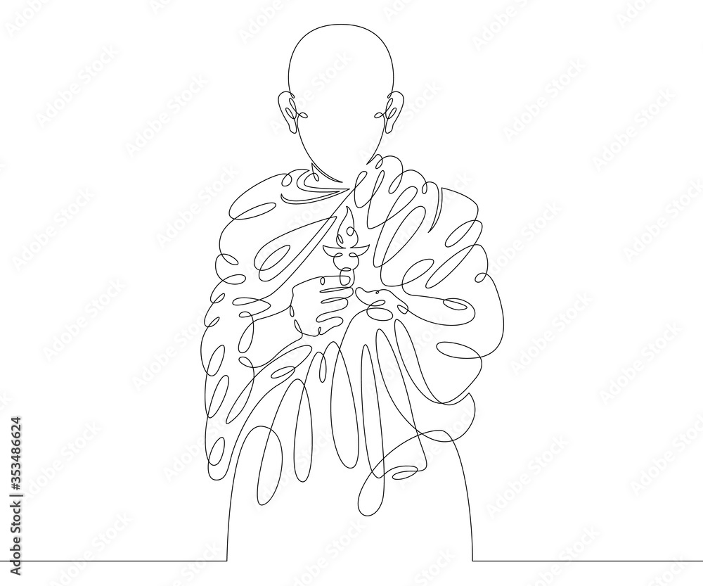 Buddhist monk holds a lighted candle in his hand