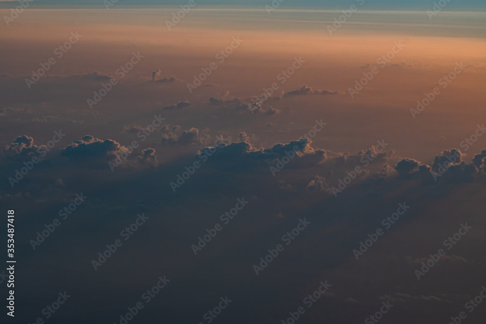 Sideways illuminated sunset clouds casting long shadows seen from an aircraft