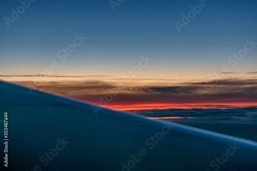 Aircraft wing silhouette seen through window in sunset sky with colorful clouds © Peter Vernon Morris