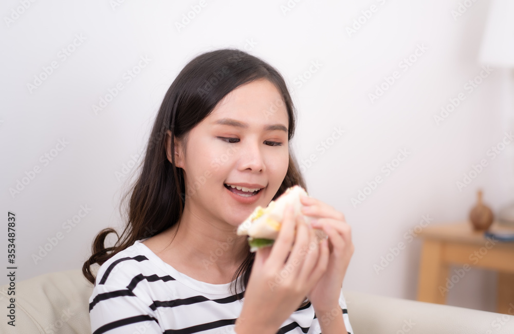 Young Asian woman eating sandwich at home. Young Asian woman eating sandwich at home.