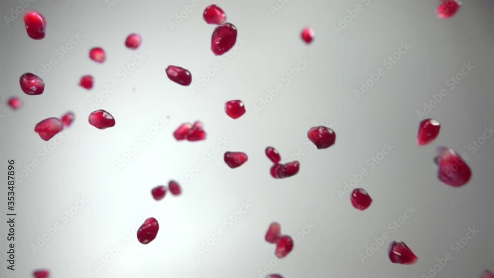 Juicy red grains of ripe pomegranate are flying diagonally on a white background in slow motion, loop footage Juicy red grains of ripe pomegranate are flying diagonally on a white background in slow motion, loop footage