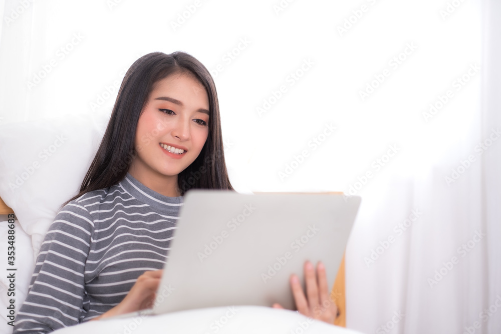 Beauty Asian woman using notebook at bedroom in the morning. Beauty Asian woman using notebook at bedroom in the morning.