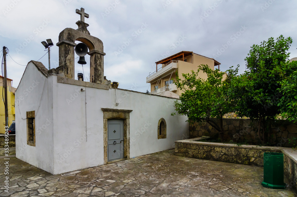 Fototapeta premium The Saint Catherine (Agia Ekaterini) greek - orthodox old chapel with it's paved backyard in Archanes town, Heraklion prefecture, Crete island - Greece. Afternoon time with cloudy sky