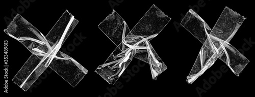 three sets of transparent sticky tapes forming the letter x or overlapping each other on black background, crumpled plastic snips, poster design overlays or elements. photo
