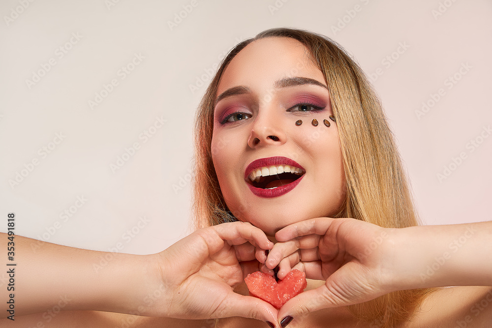 Girl with a heart from the pulp of watermelon, with a beautiful makeup, closeup, isolated. Beauty fashion concept Girl with a heart from the pulp of watermelon, with a beautiful makeup, closeup, isolated. Beauty fashion concept