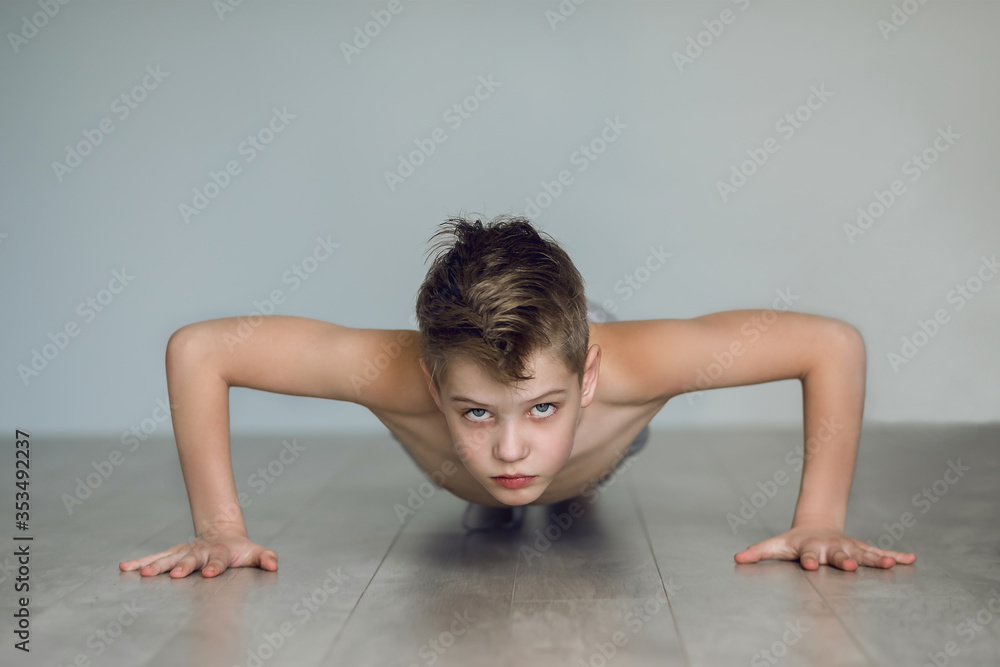 The boy is pushing up from the floor at home. Quarantine and sport concept. The child develops willpower and mode. The boy is pushing up from the floor at home. Quarantine and sport concept. The child develops willpower and mode.