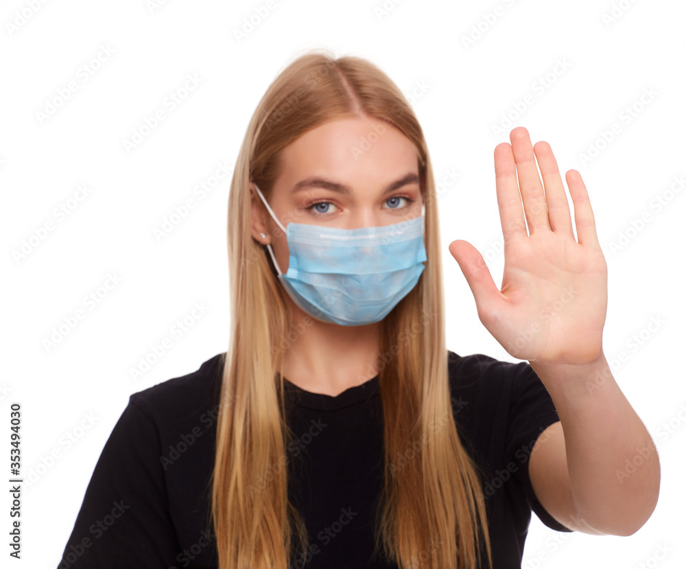 young woman in medical protective mask shows a stop gesture with hand on studio background young woman in medical protective mask shows a stop gesture with hand on studio background