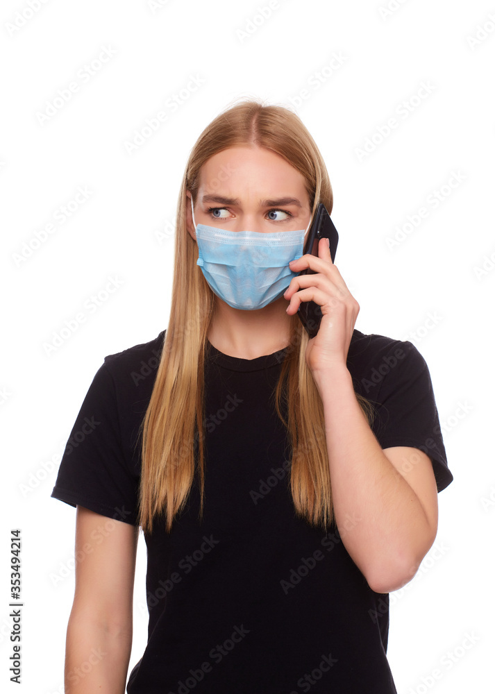 The girl in the medical mask is in home isolation and is talking on the phone with relatives. The girl in the medical mask is in home isolation and is talking on the phone with relatives.