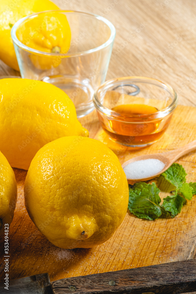 Freshly squeezed lemon juice and mint leave in clear glass cup on wooden chopping board and clean white marble background. Healthy Fruit juices that are high in vitamin C.