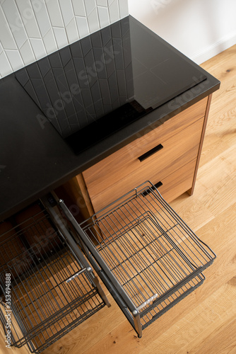 Cargo drawer in a wooden brown kitchen with a black countertop