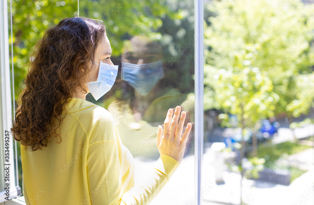 Young woman in isolation at home near window Young woman in isolation at home near window