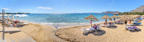 Pefkos beach with holiday-makers, sun beds and umbrellas in village of Pefkos - PANORAMA (Rhodes, Greece)