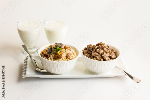 Traditional Turkish Islamic Feast,braised meat and rice in stylish white bowls on the white surface with fabric napkin and cold drink.