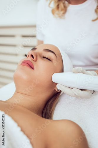 Beautiful and attractive adult woman receiving professional facial care beauty treatment with peeling mask.