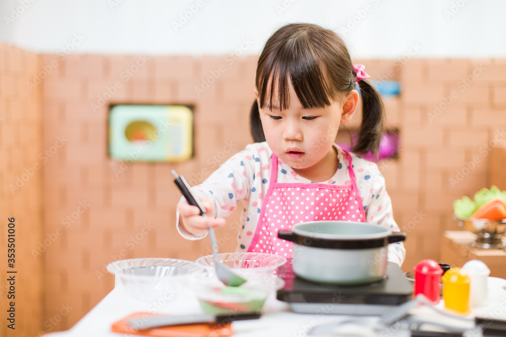 toddler girl pretend play food preparing role against cardboard blocks kitchen background toddler girl pretend play food preparing role against cardboard blocks kitchen background