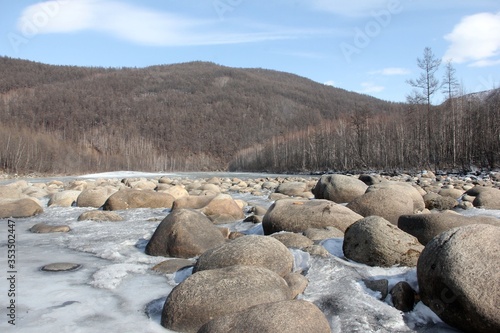 A river in Yakutia with large stones. The river in Yakutia, against the background of the forest. A river in the north in summer.