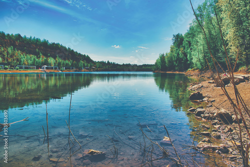 A lake with crystal clear water. The concept of rest by the lake  rest by the reservoir. Beautiful lake among trees  forest.